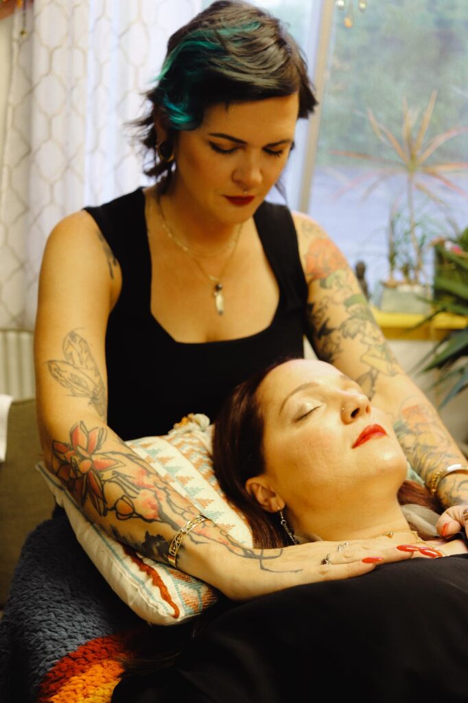 An energy healer wearing a black tank top providing reiki to a client who is relaxed and has their eyes closed at Wonderland Healing Co in Menomonee Falls, Wisconsin