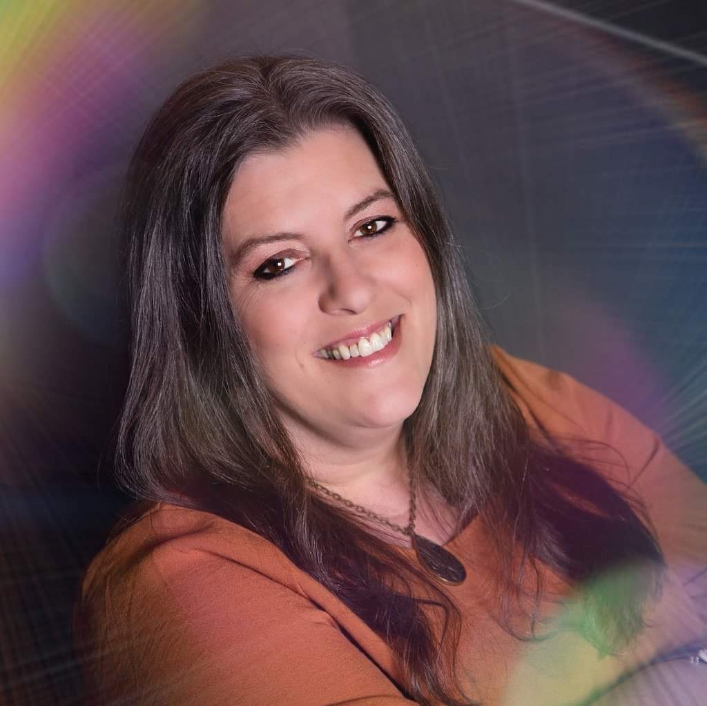 Headshot of Stacy, Psychic Medium and spiritual teacher, team member of Wonderland Healing in Menomonee Falls, WI, wearing a rust orange shirt and smiling