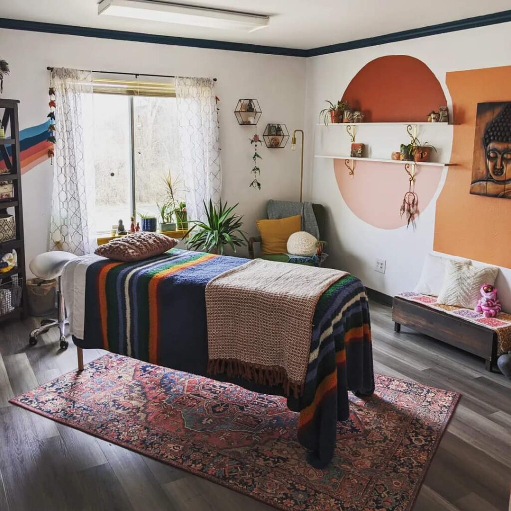 Beautiful, relaxing studio with plants, rust, pink and orange paint, hardwood floor and vintage rug under the comfortable bed where reiki and energy healing take place at Wonderland Healing Co in Menomonee Falls, WI